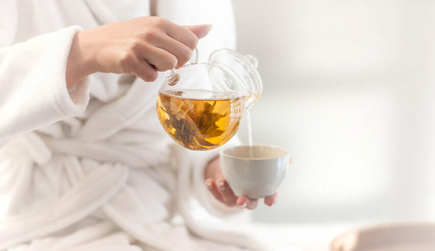 Woman in robe pouring tea into mug
